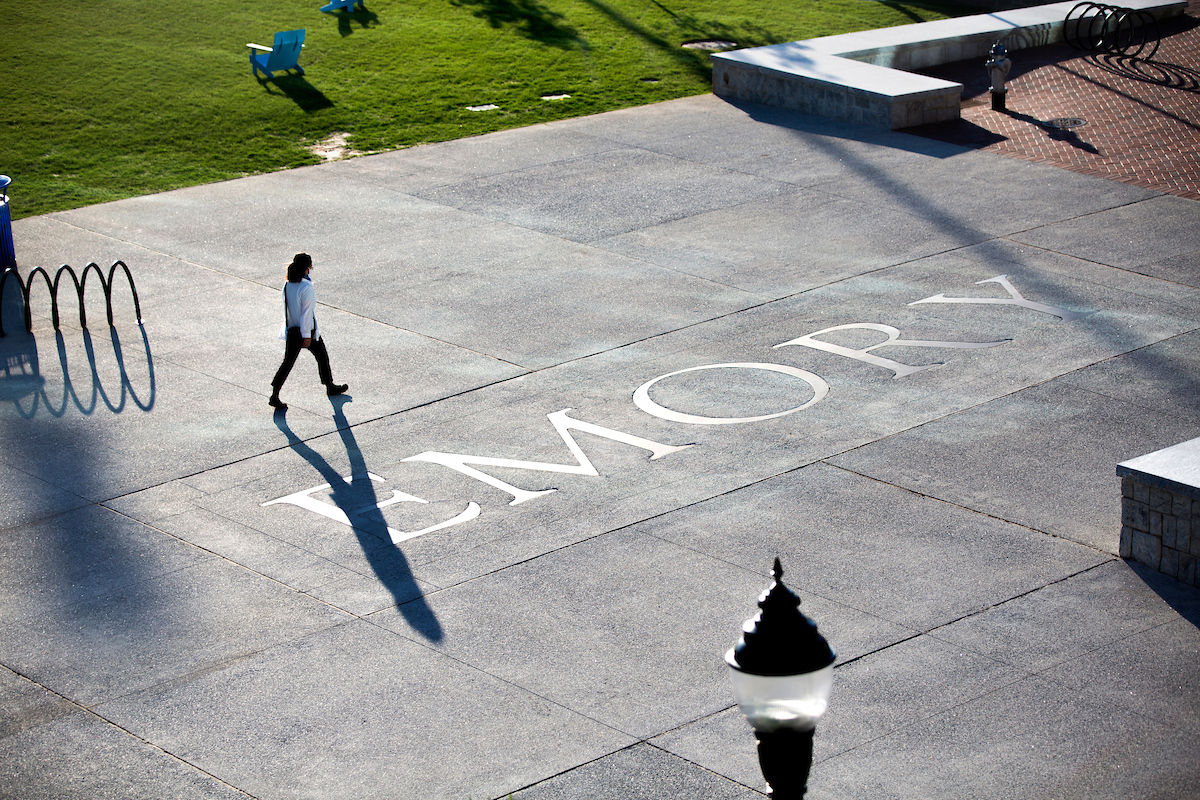 student walking on a sidewalk that says emory